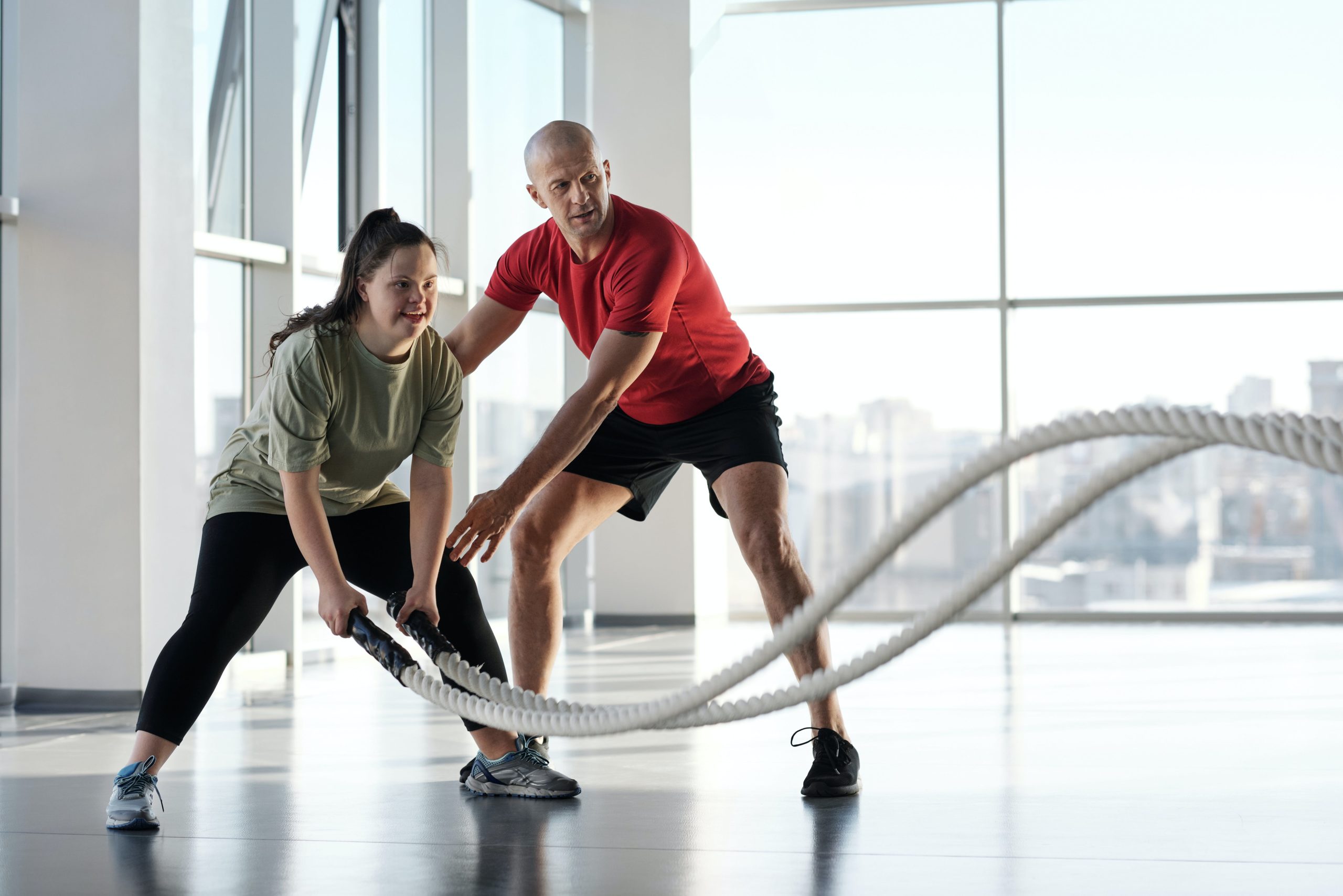 A coach assisting a woman with her rope training