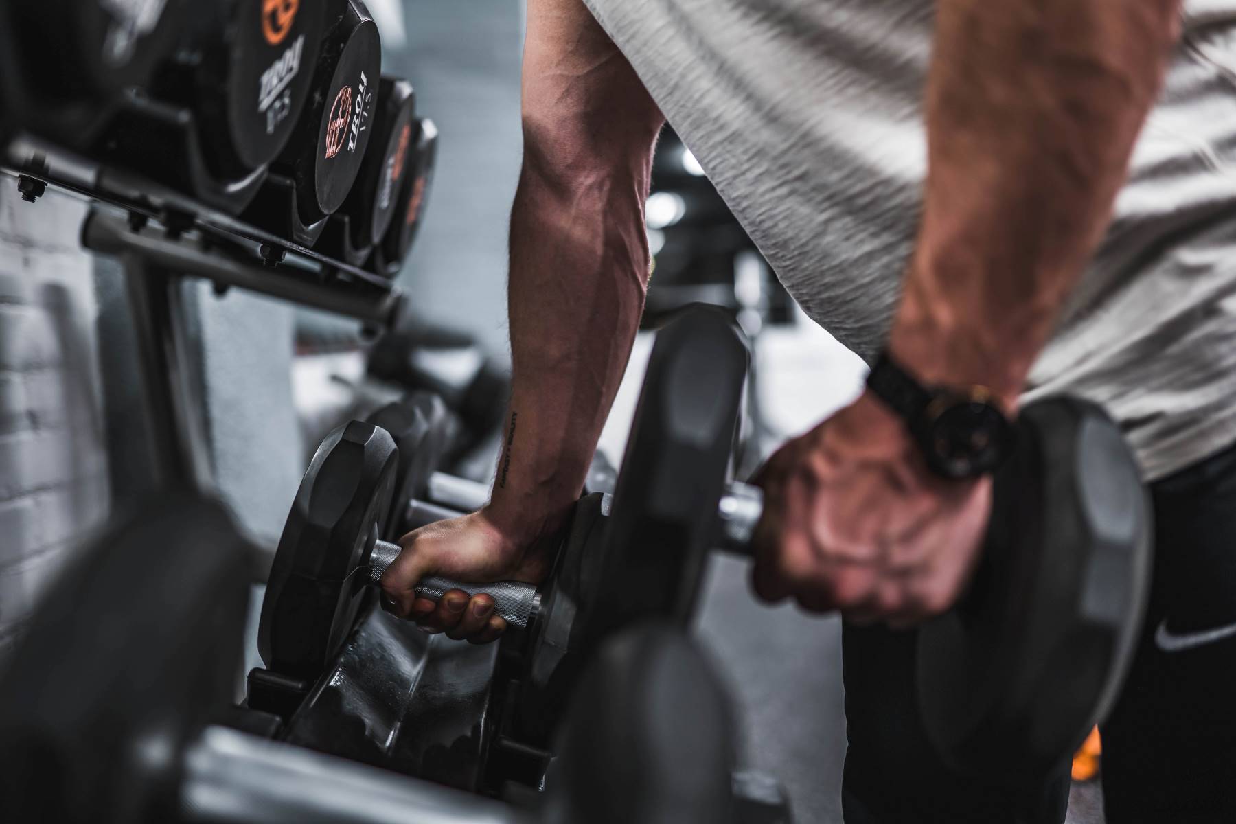 Man getting weights off a dumbbell rack